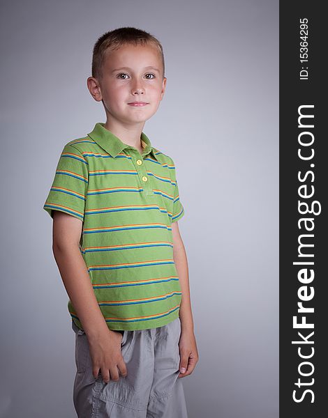 Blonde kid with gray pants and green blouse with stripes