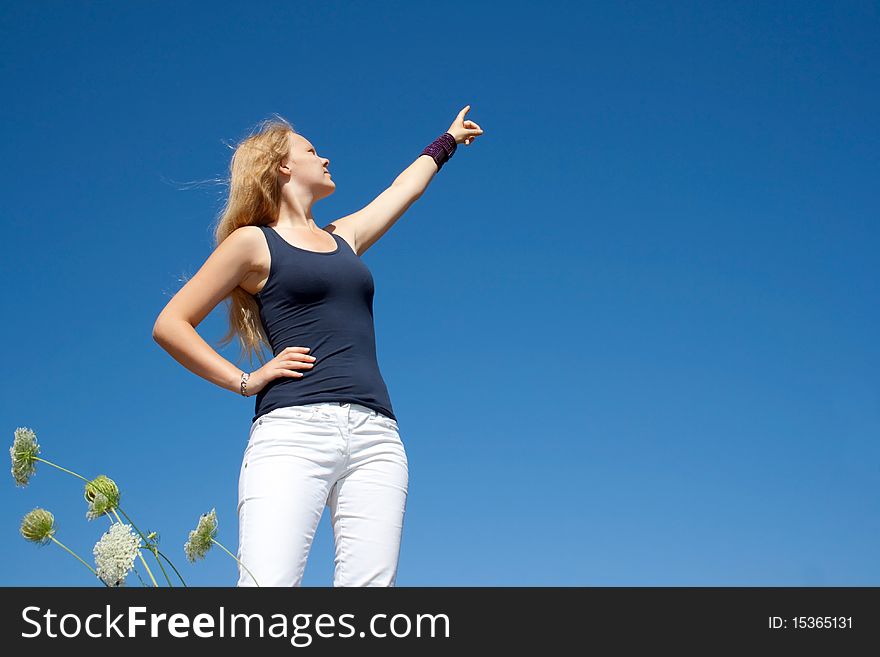 Pretty lady points to the right side in front of a blue sky