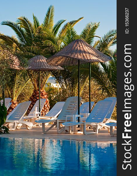 Chaise longues under beach umbrellas near the swimming pool