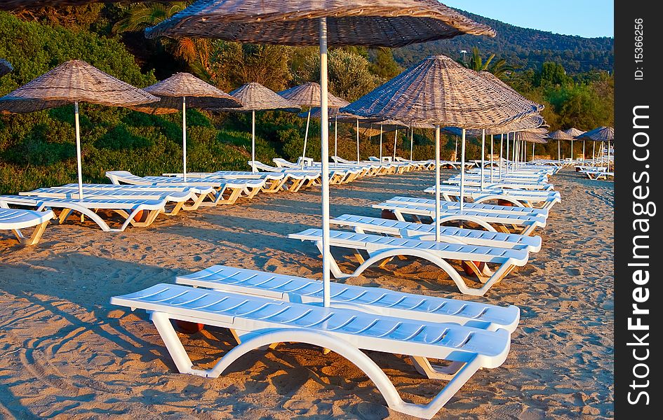 Rows of chaise longues under the beach umbrellas. Rows of chaise longues under the beach umbrellas
