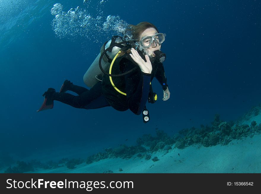 Female scuba diver swims in blue water