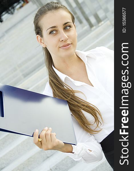 Attractive young businesswoman smiling with a folder. Attractive young businesswoman smiling with a folder