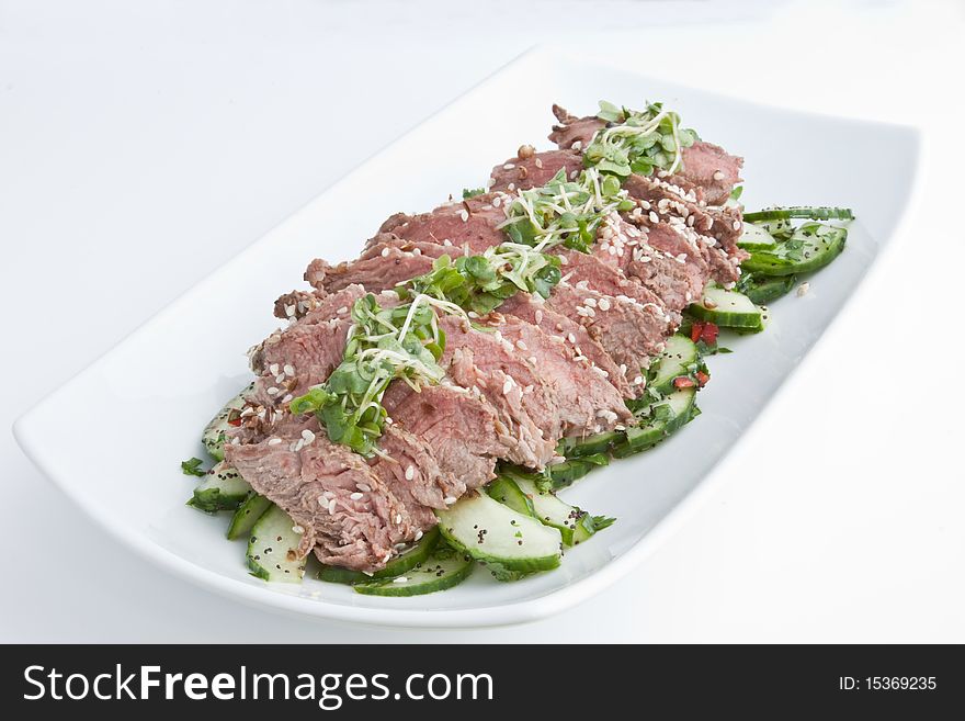 A salad of sliced rare fillet steak on a bed od cucumber garnished with cress. A salad of sliced rare fillet steak on a bed od cucumber garnished with cress