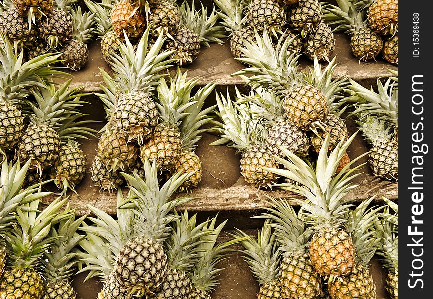 Rows and stacks of pineapple for sale in a market in Asia.