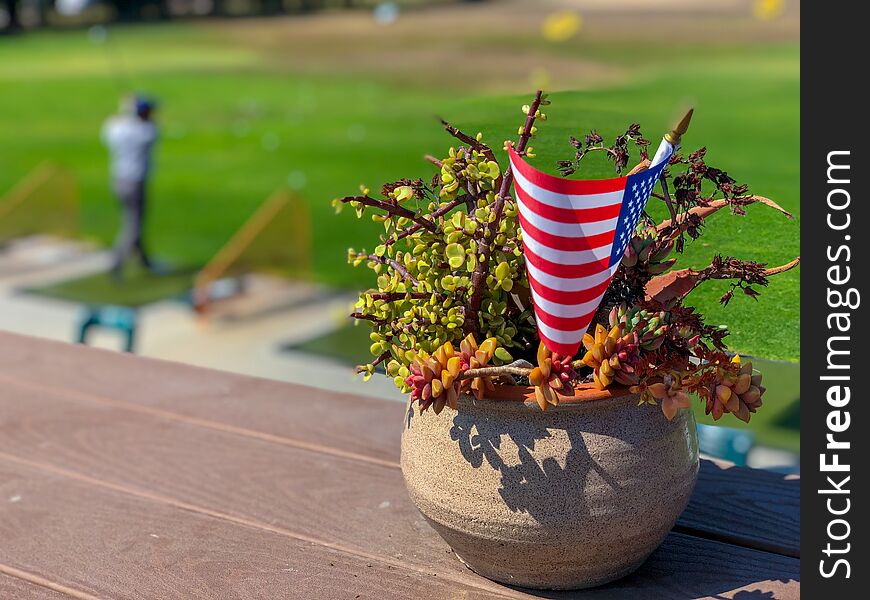 Patriotic flower pot with American flags and golfer on the background.