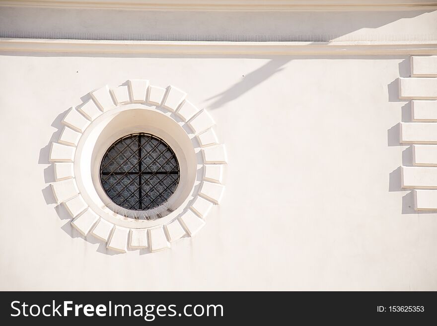 Beautiful round window on white wall of a house and shadow on it