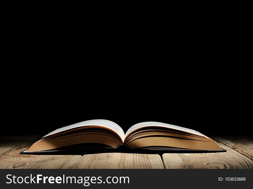 Open Book On A Wooden Table And Black Background  With Copy Space For Your Text