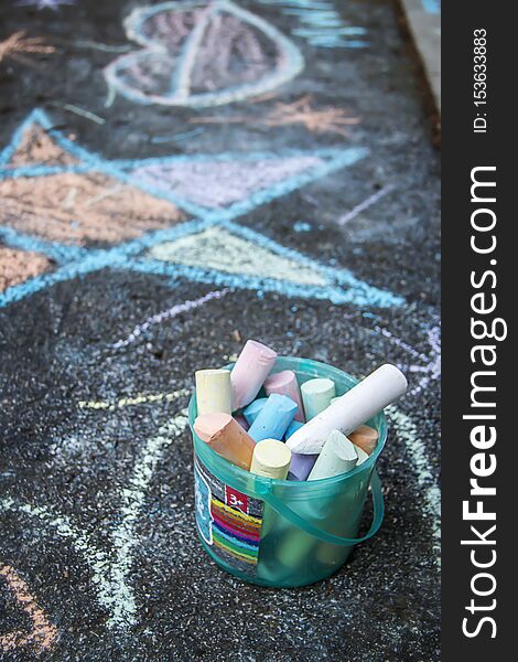 A picture of colorful chalk drawings on a sidewalk in the summer