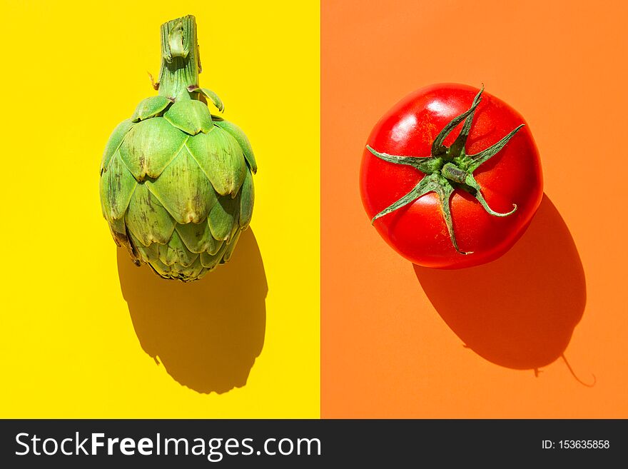 Ripe green artichoke red tomato on duotone yellow orange background with hard light harsh shadows. Trendy funky creative style for food poster banner of Mediterranean cuisine vegan concept