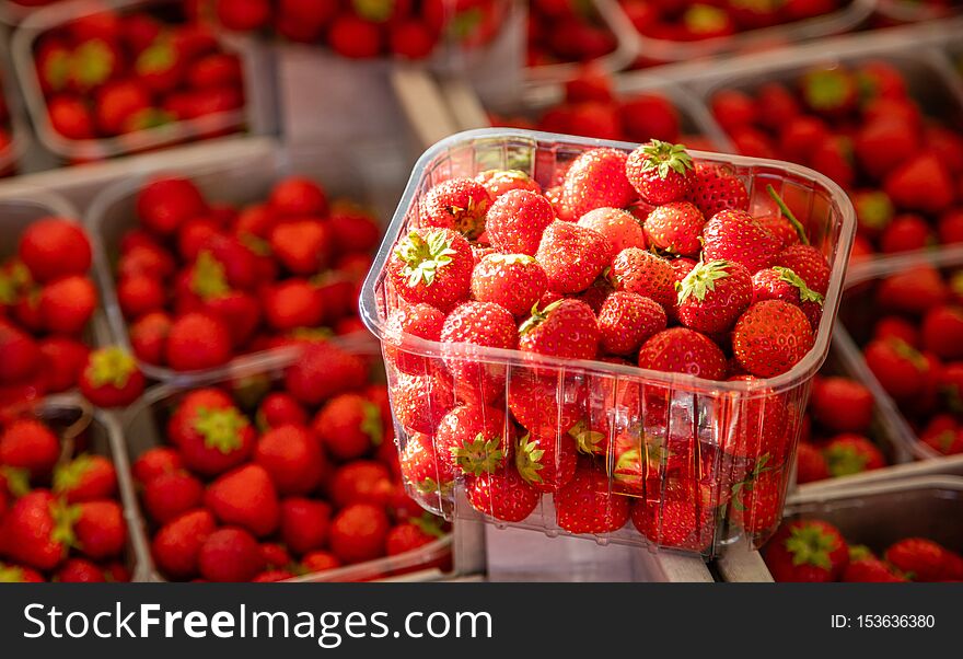 Strawberries in plastic containers at farmers market, background, texture