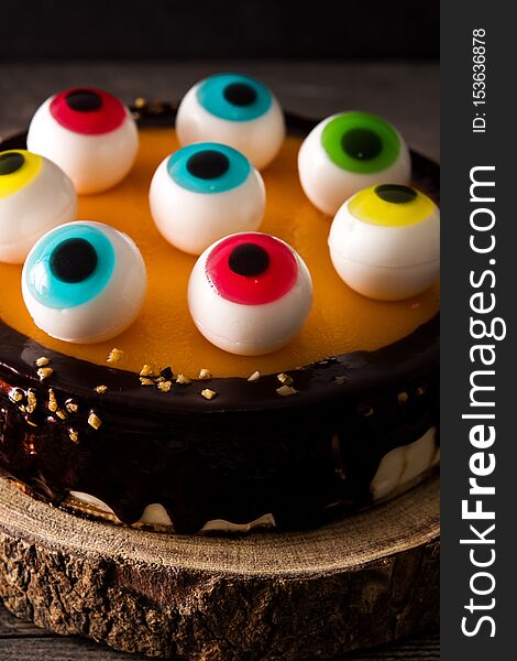 Halloween cake with candy eyes decoration on wooden table. Close up