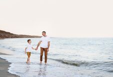 Father And Son Go By The Hand Along The Sea Coast. Family Vacation. Friendship Royalty Free Stock Photo