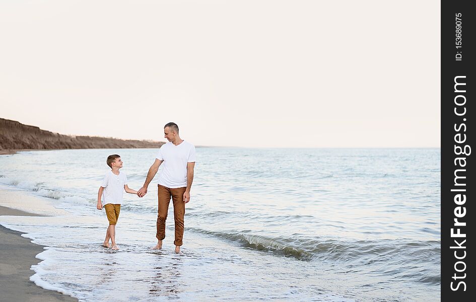 Father and son go by the hand along the sea coast. Family vacation. Friendship.