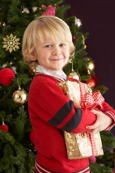 Young Boy Holding Gift In Front Of Christmas Tree Stock Images Young Boy Holding Gift In Front Of Christmas Tree Stock Images