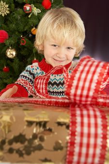 Boy Holding Gift In Front Of Christmas Tree Stock Photography