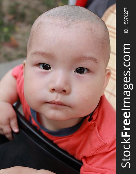 A lovely bareheaded chinese baby sitting in a stroller. A lovely bareheaded chinese baby sitting in a stroller