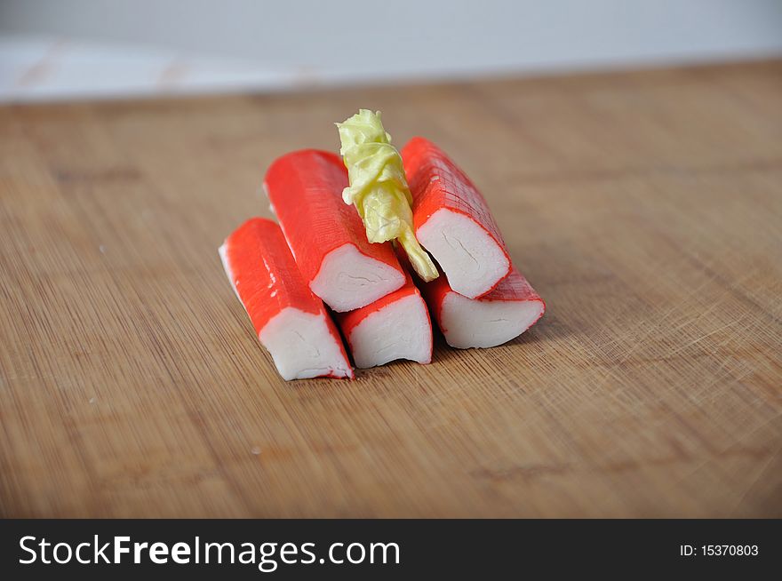 Pile of surimi with lettuce on wood desk. Pile of surimi with lettuce on wood desk