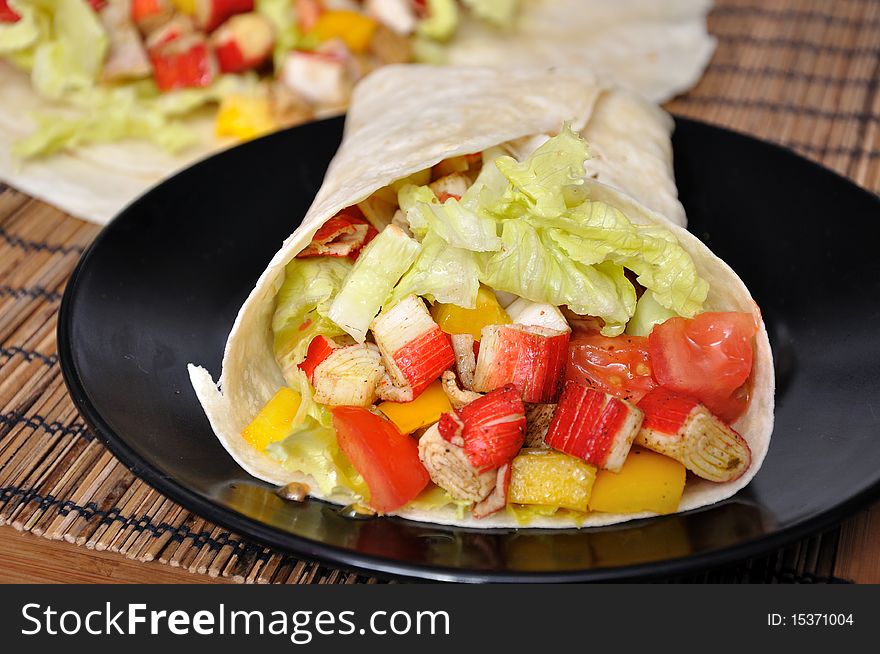 Clsoeup surami kebab with lettuce, pepper and tomato on black plate. Clsoeup surami kebab with lettuce, pepper and tomato on black plate.