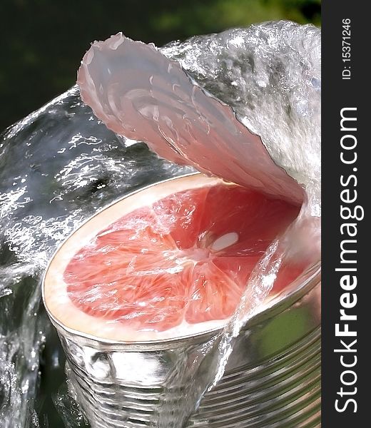 Slice of grapefruit i is filled a opened tin in waterstream, closeup, conceptual. Slice of grapefruit i is filled a opened tin in waterstream, closeup, conceptual