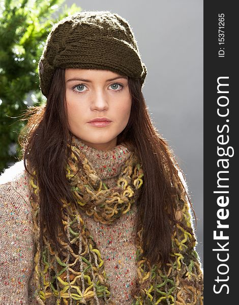 Fashionable Teenage Girl Wearing Cap And Knitwear In Studio In Front Of Christmas Tree