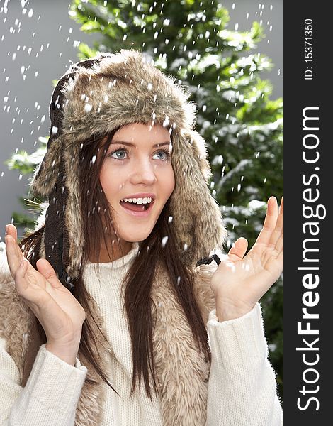 Fashionable Teenage Girl Wearing Cap And Knitwear In Studio In Front Of Christmas Tree