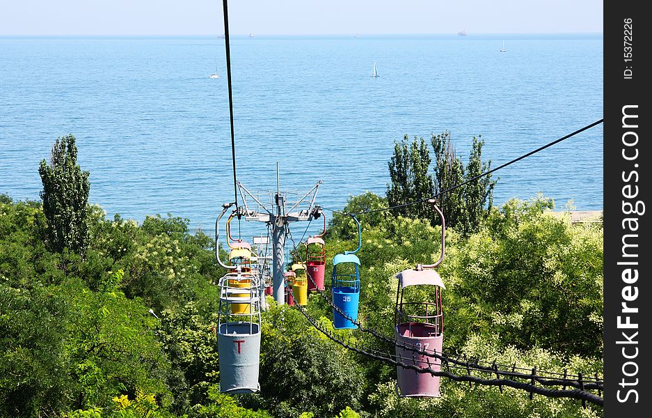 Funicular with empty cabs over trees near sea