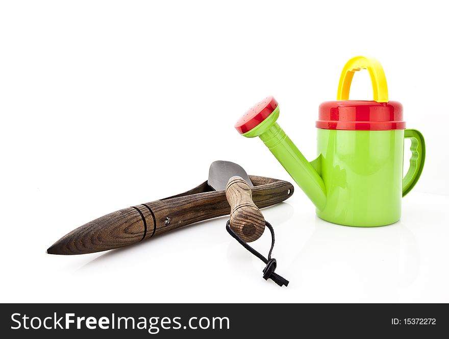 Colorful watering can and gardening tools over white background