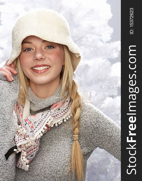 Fashionable Teenage Girl Wearing Cap And Knitwear In Studio In Front Of Christmas Tree