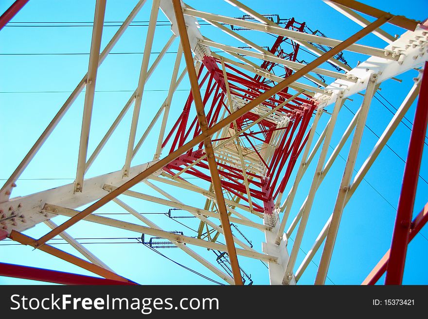 Top of the red and white high voltage electricity pylon against the blue sky. Top of the red and white high voltage electricity pylon against the blue sky