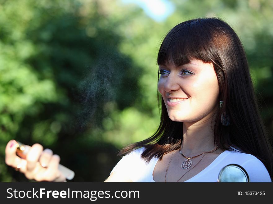 Pretty lady spraying a parfume on nature. Pretty lady spraying a parfume on nature