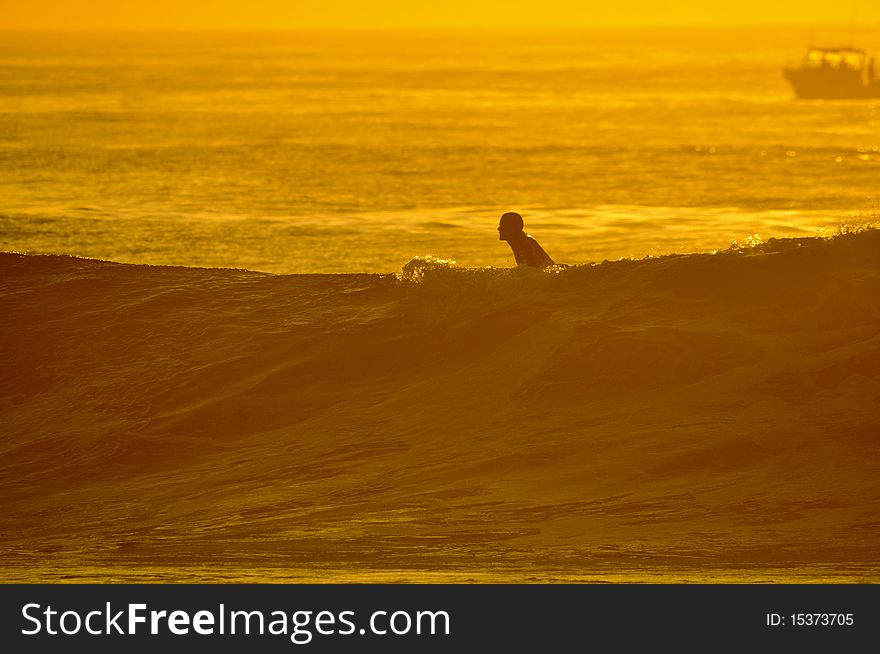 Surfer on wave silhouette at sunrise