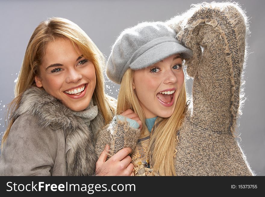 Two Fashionable Teenage Girls Wearing Cap And Knitwear In Studio. Two Fashionable Teenage Girls Wearing Cap And Knitwear In Studio