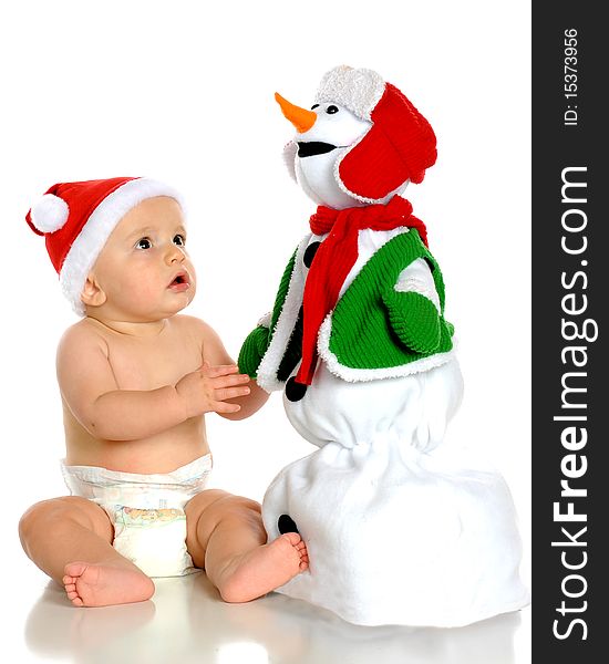 A handsome baby boy in a Santa hat enthralled by a toy snowman. Isolated on white. A handsome baby boy in a Santa hat enthralled by a toy snowman. Isolated on white.