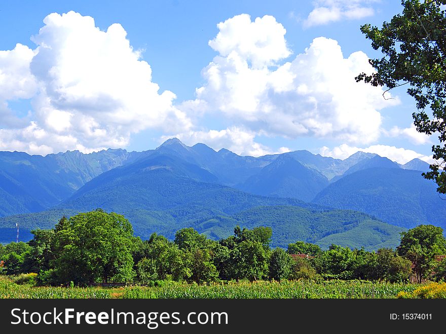 Beautiful landscape with green field, green forest, high mountains and cloudy sky. Beautiful landscape with green field, green forest, high mountains and cloudy sky