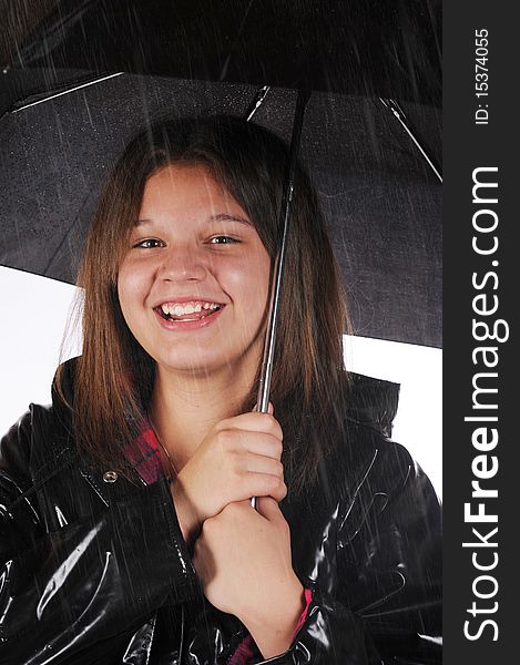 A young teen happily in her raincoat and under a black umbrella  in the rain. A young teen happily in her raincoat and under a black umbrella  in the rain.