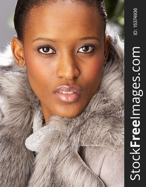 Fashionable Woman Wearing Fur Coat In Studio In Front Of Christmas Tree