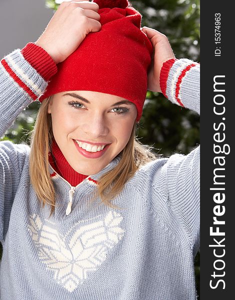 Fashionable Teenage Girl Wearing Cap And Knitwear In Studio In Front Of Christmas Tree. Fashionable Teenage Girl Wearing Cap And Knitwear In Studio In Front Of Christmas Tree