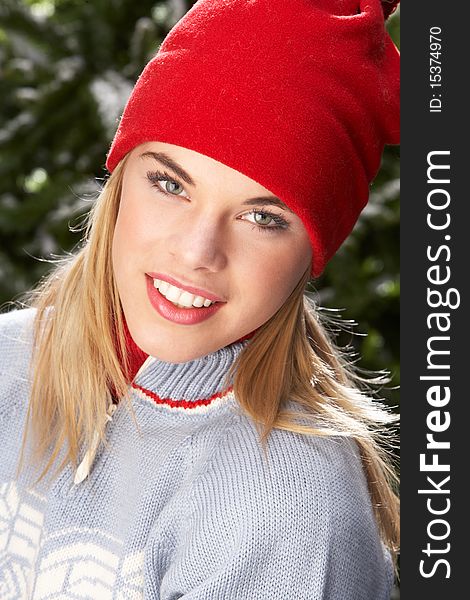 Fashionable Teenage Girl Wearing Cap And Knitwear In Studio In Front Of Christmas Tree. Fashionable Teenage Girl Wearing Cap And Knitwear In Studio In Front Of Christmas Tree