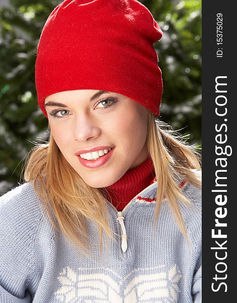 Fashionable Teenage Girl Wearing Cap And Knitwear In Studio In Front Of Christmas Tree. Fashionable Teenage Girl Wearing Cap And Knitwear In Studio In Front Of Christmas Tree