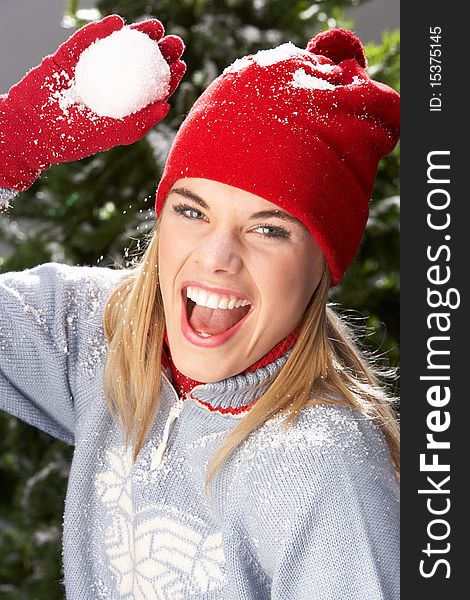 Fashionable Teenage Girl Wearing Cap And Knitwear Holding Snowball In Studio In Front Of Christmas Tree. Fashionable Teenage Girl Wearing Cap And Knitwear Holding Snowball In Studio In Front Of Christmas Tree