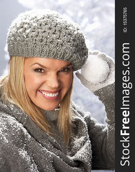 Fashionable Woman Wearing Cap And Knitwear Holding Snowball In Studio In Front Of Christmas Tree. Fashionable Woman Wearing Cap And Knitwear Holding Snowball In Studio In Front Of Christmas Tree