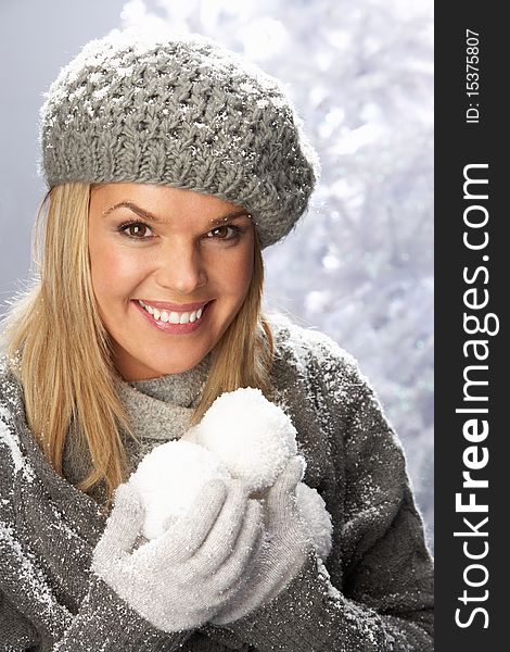 Fashionable Woman Wearing Cap And Knitwear Holding Snowball In Studio In Front Of Christmas Tree. Fashionable Woman Wearing Cap And Knitwear Holding Snowball In Studio In Front Of Christmas Tree