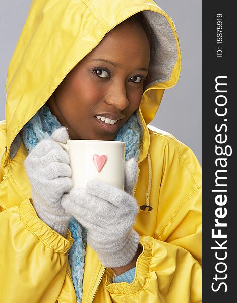 Young Woman Drinking Hot Drink Wearing Yellow Raincoat