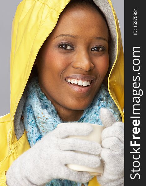 Young Woman Drinking Hot Drink Wearing Yellow Raincaot