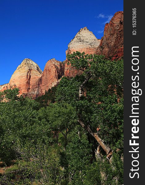 Clear sky, mountain peaks and rich greens compose different levels of colors on the signature of Zion National Park landscape near park entrance. Clear sky, mountain peaks and rich greens compose different levels of colors on the signature of Zion National Park landscape near park entrance.