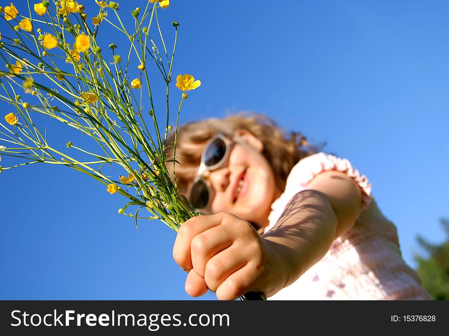 The girl has extended a hand forward with a bouquet from yellow wild flowers against the sky. The girl has extended a hand forward with a bouquet from yellow wild flowers against the sky