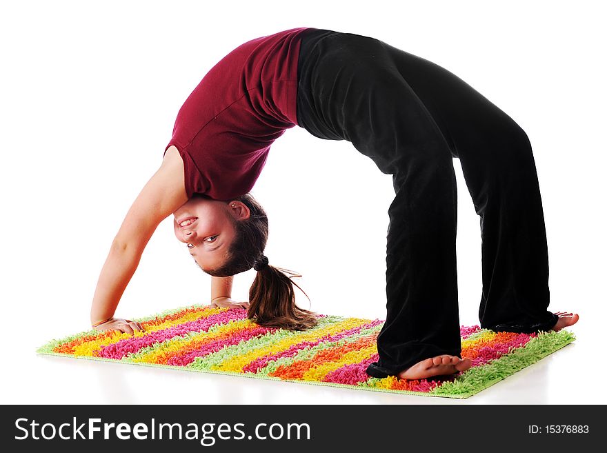 A happy preteen looking back at the viewer while doing a backbend on a bright,striped rug. Isolated on white. A happy preteen looking back at the viewer while doing a backbend on a bright,striped rug. Isolated on white.