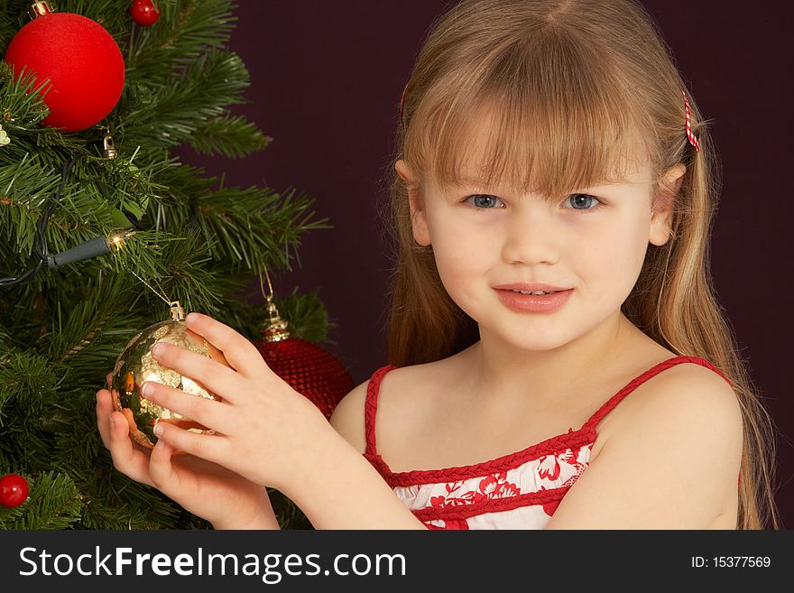 Young Girl Decorating Christmas Tree At Camera