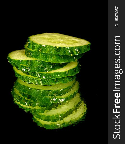 Cucumber slices on the black background with water drops
