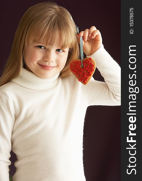 Young Girl Holding Heart Shaped Cookie In Studio Smiling
